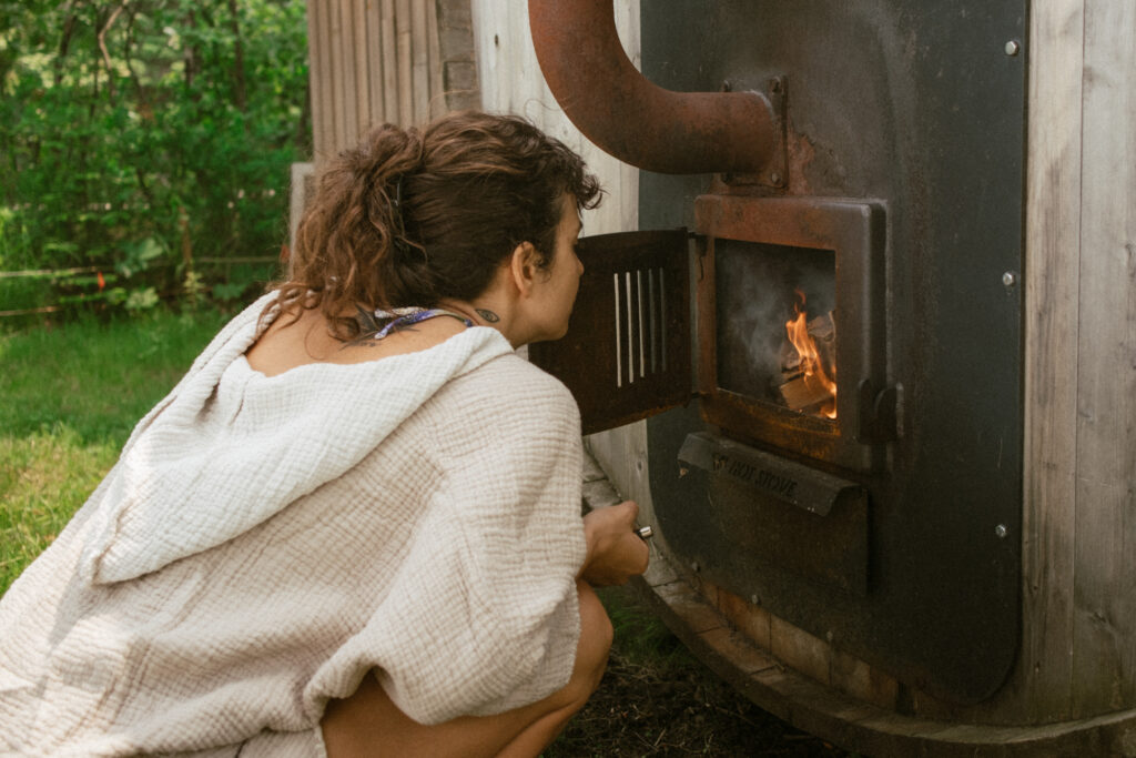 Woman stoking the fire for an outdoor sauna