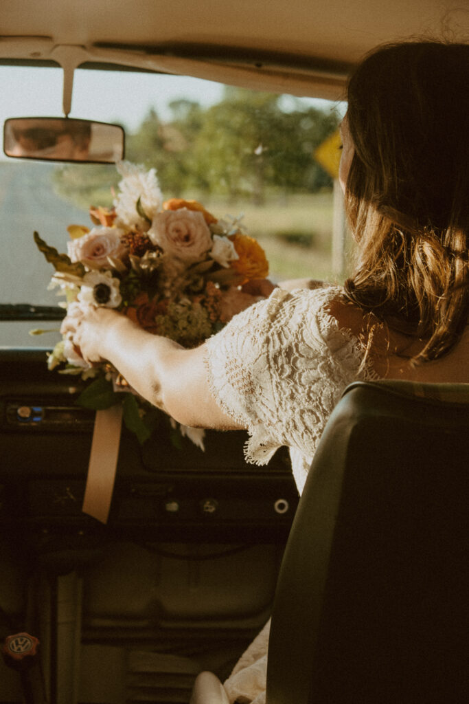 Bride looks at her bouquet of flowers in the car