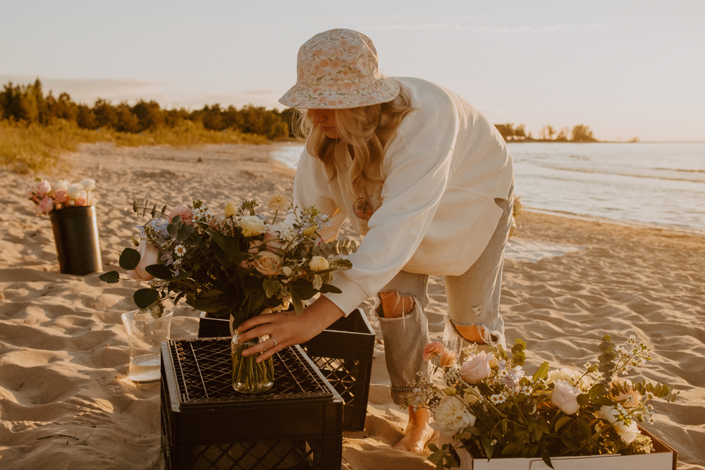 Florist working behind-the-scenes to set up a beach picnic with florals
